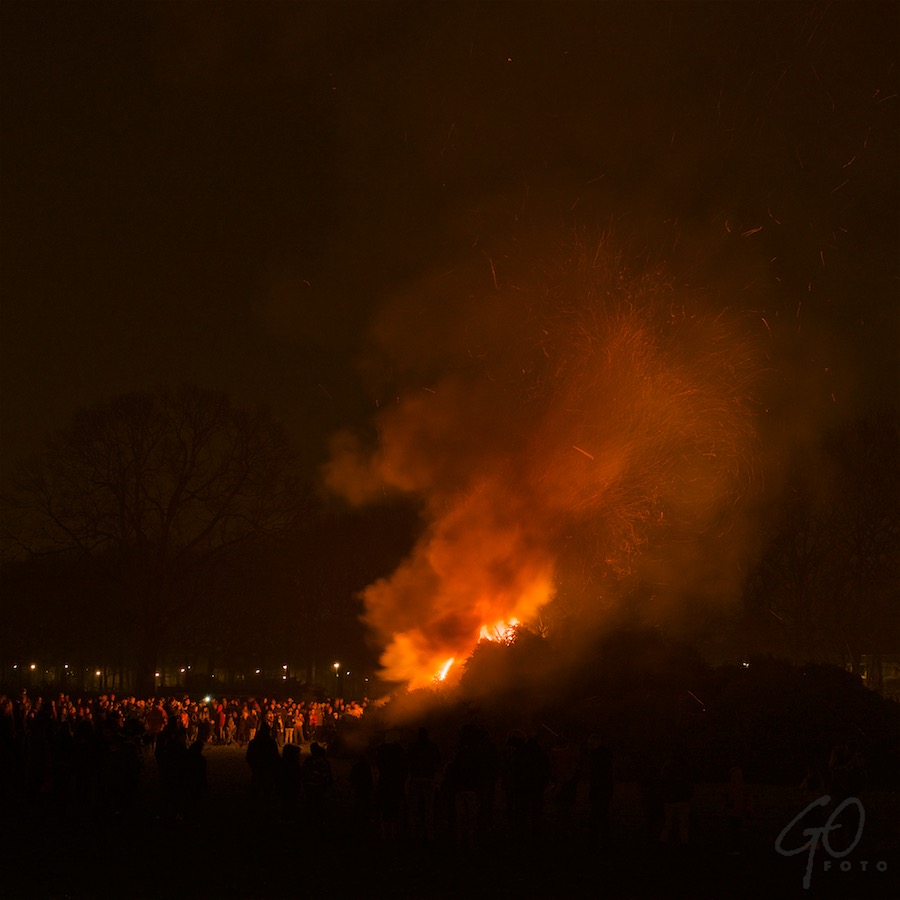 Foto van kerstbomenverbranding op het evenemententerrein in Hoogland. De lucht kleurt vuurrood.