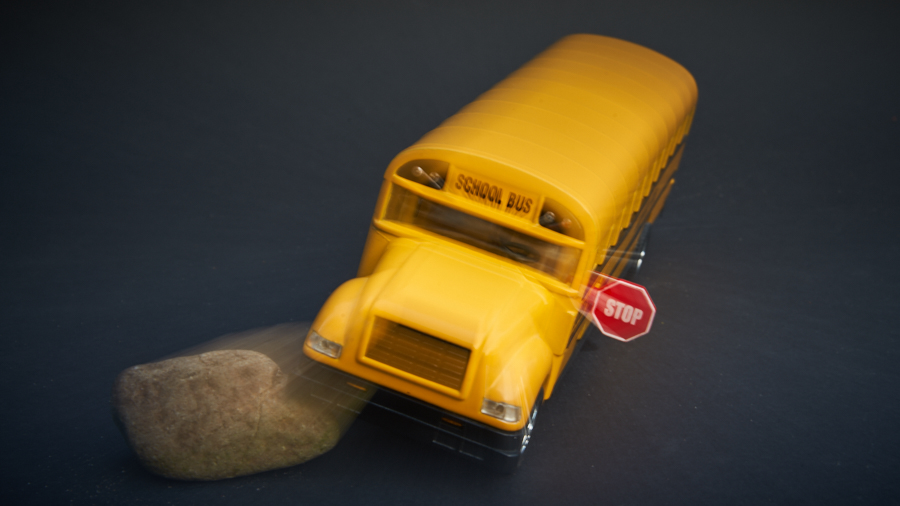 Foto van een miniatuur schoolbus die tegen een steen botst