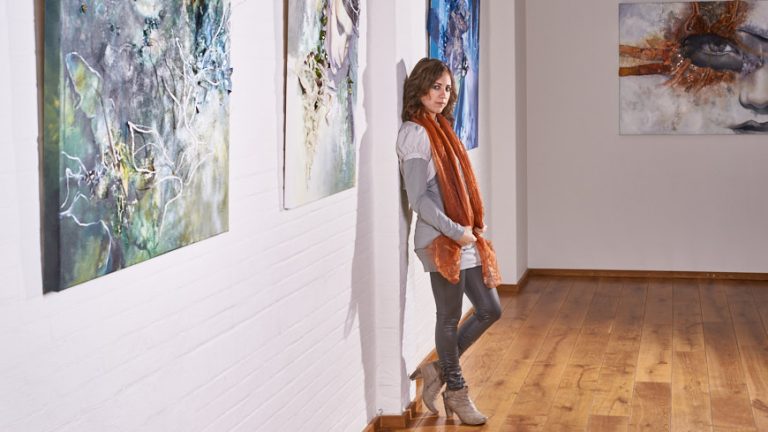 Kunstenaar Lora Harreveld tussen haar schilderijen