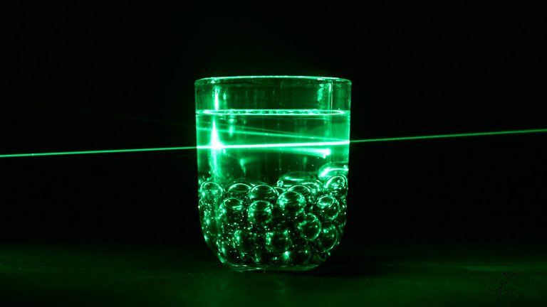 Glas water met knikkers in fel groen licht