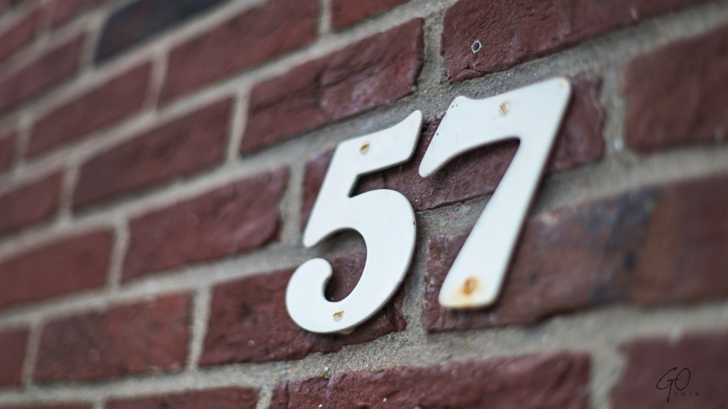 Huisnummer 57 op een stenen muur
